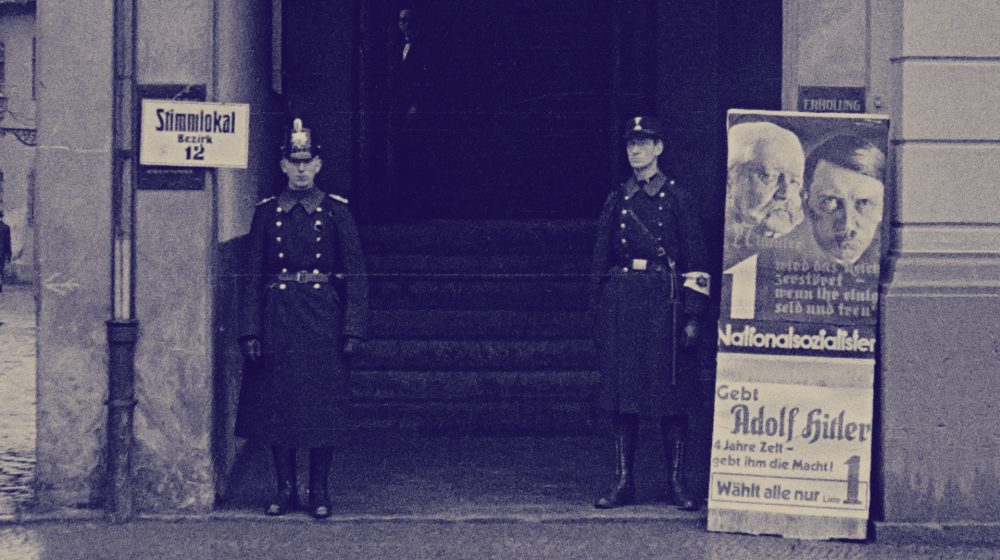 Schutzpolizist und „Hilfspolizist“ der SA vor Wahllokal (Foto: Wilhelm Walther, CC-BY-SA 4.0)  