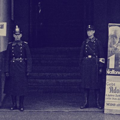 Schutzpolizist und „Hilfspolizist“ der SA vor Wahllokal (Foto: Wilhelm Walther, CC-BY-SA 4.0)  