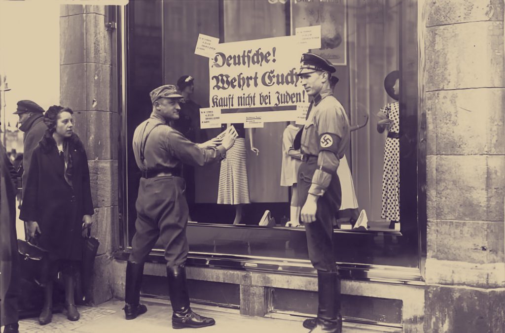 a Nazi stormtrooper plasters a boycott poster on a Jewish shop window in April 1933